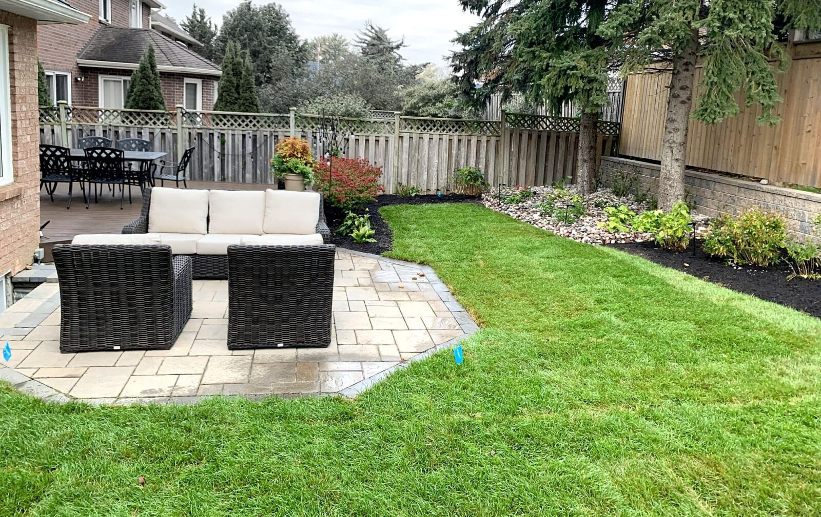 Lomota Gardening Project 4 -After. Beautifully manicured lawn and garden with comfortable wicker chairs and sofa on octagonal patio stones.