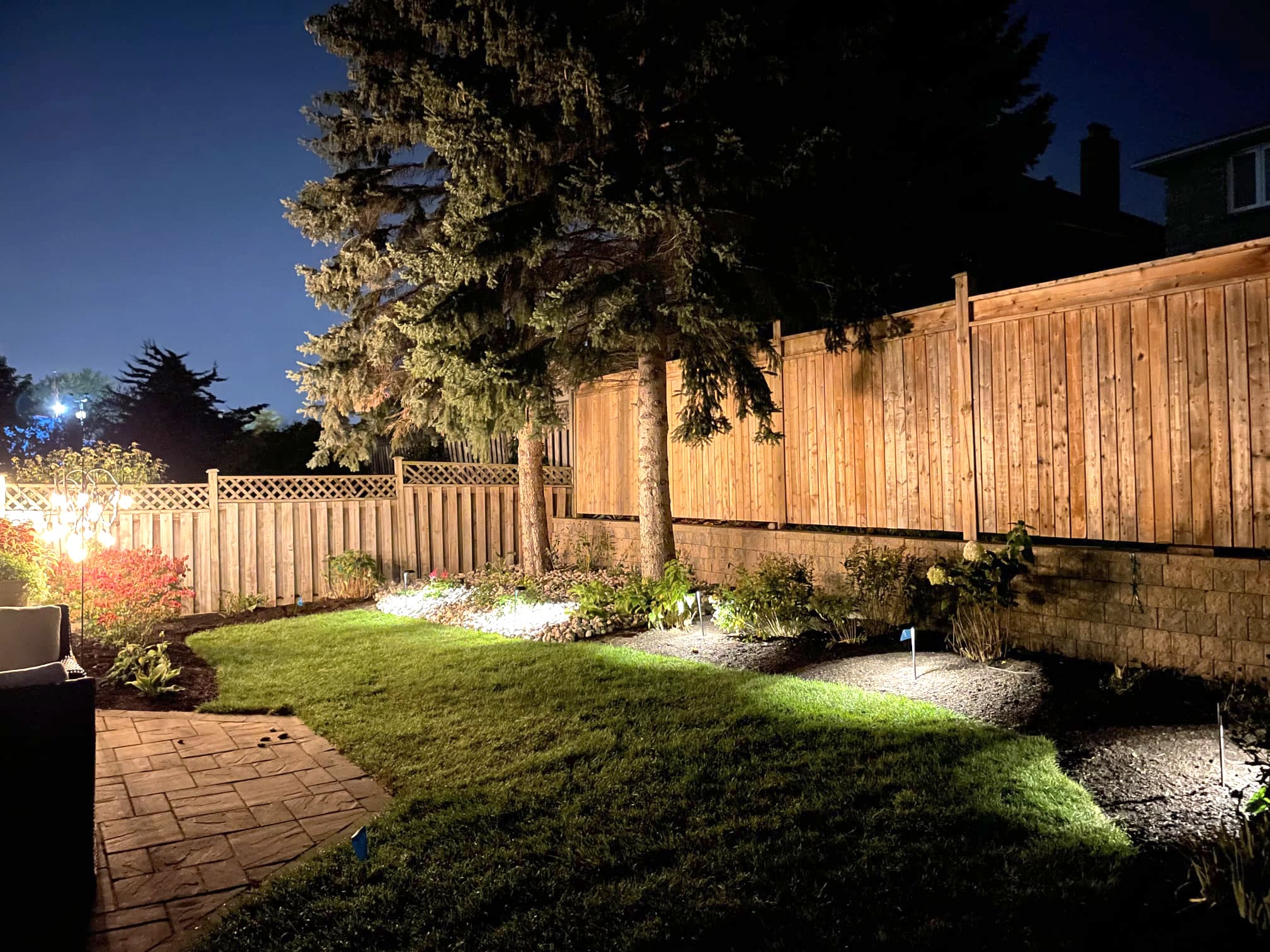 Lomota Gardening Project 4 -After. Night shot of beautifully manicured garden with ground level lighting and patio stones.
